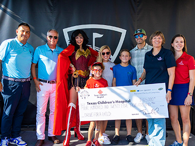 Nine people holding a check in front of a background.