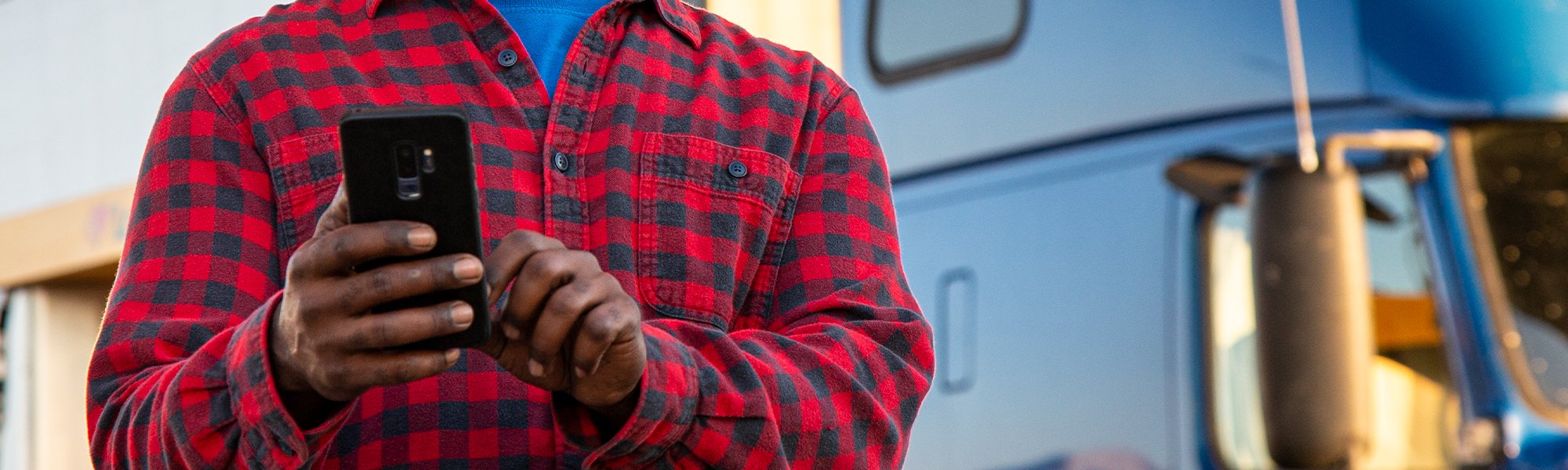 A person holding a phone in front of a commercial truck