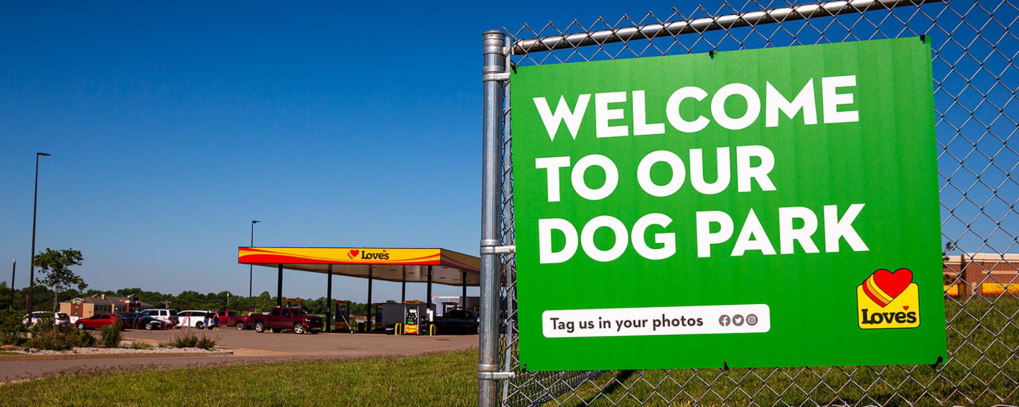 A photo of a "Welcome to our dog park" sign on the fence of a dog park