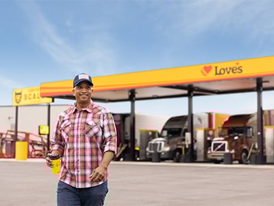 a professional driver walking into a love's with the diesel canopy in the background