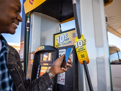 Love's customer looking at phone in front of fuel discount promo at gas pump
