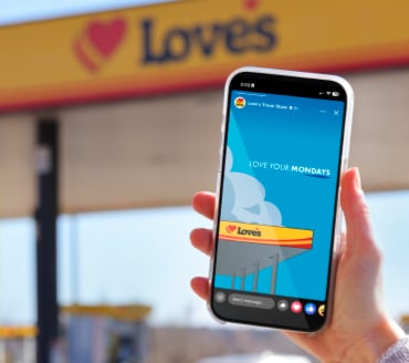A phone with a "Love Your Mondays" graphic on it in front of a Love's gas canopy
