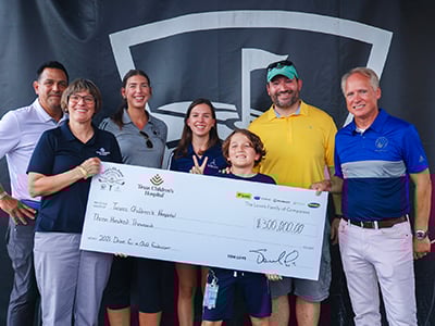 Musket and Trillium employees giving big check to Texas Childrens Hospital at golf tournament with patient and father