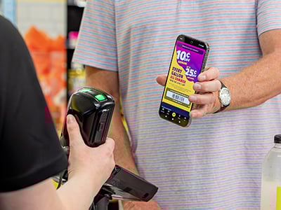 A customer holding a phone with the Love's App pulled up getting scanned in a store