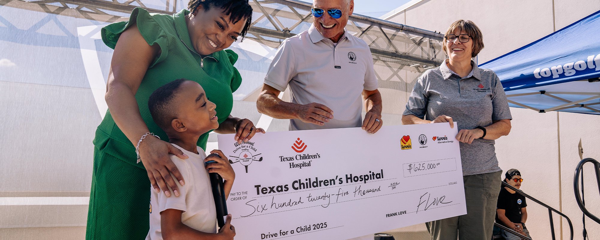 Child receiving Texas Children's Hospital check from Musket Corp. and Love's Alternative Energy annual fundraiser golf tournament