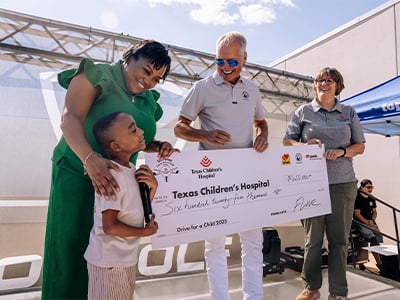 Child receiving Texas Children's Hospital check from Musket Corp. and Love's Alternative Energy annual fundraiser golf tournament