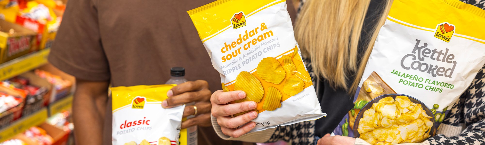 A customer holding Love's Chips and Premium Water in a Travel Stop