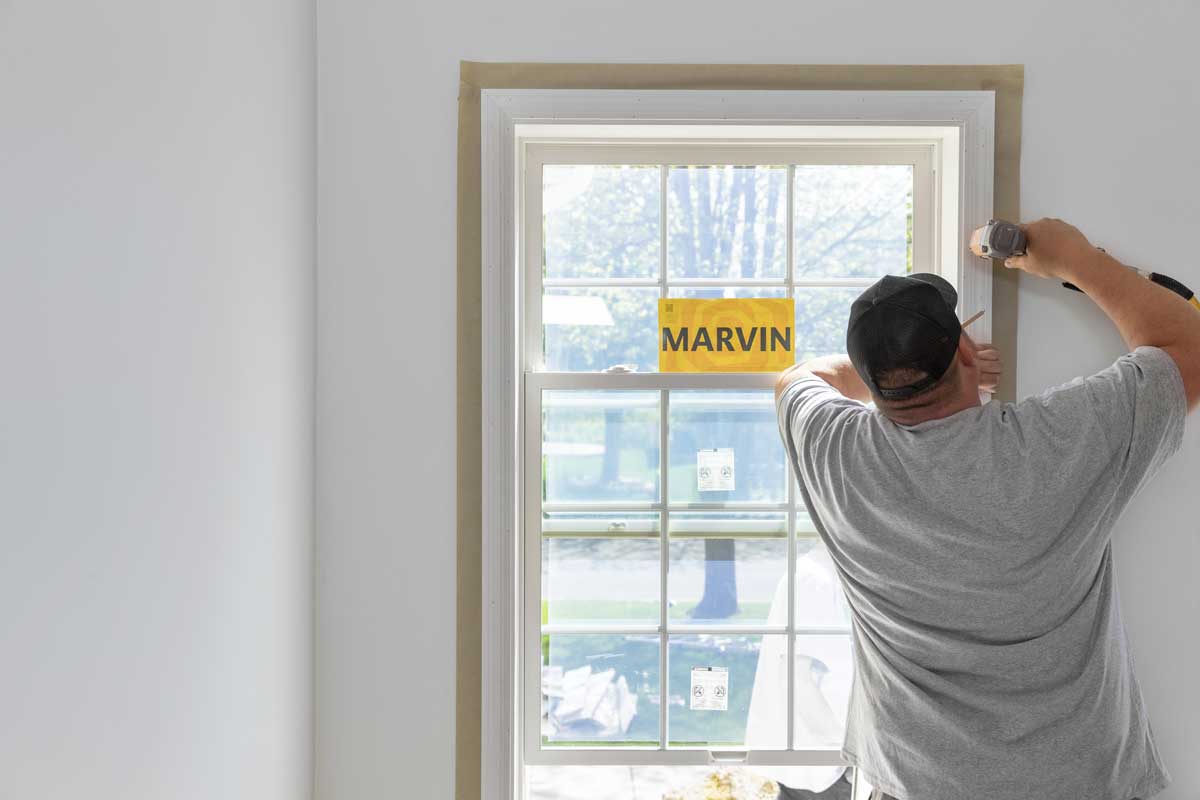 A man installing a Marvin Essential double hung replacement window 