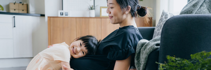 A pregnant woman with her young daughter, who is listening to her baby bump