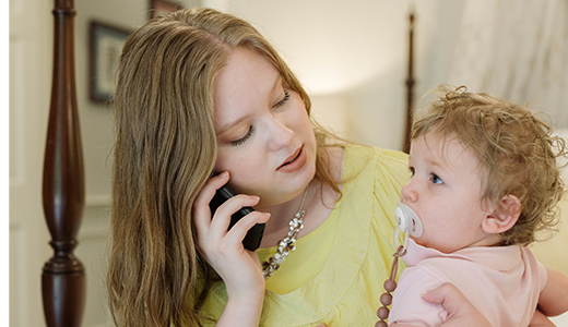 woman on the phone holding a baby
