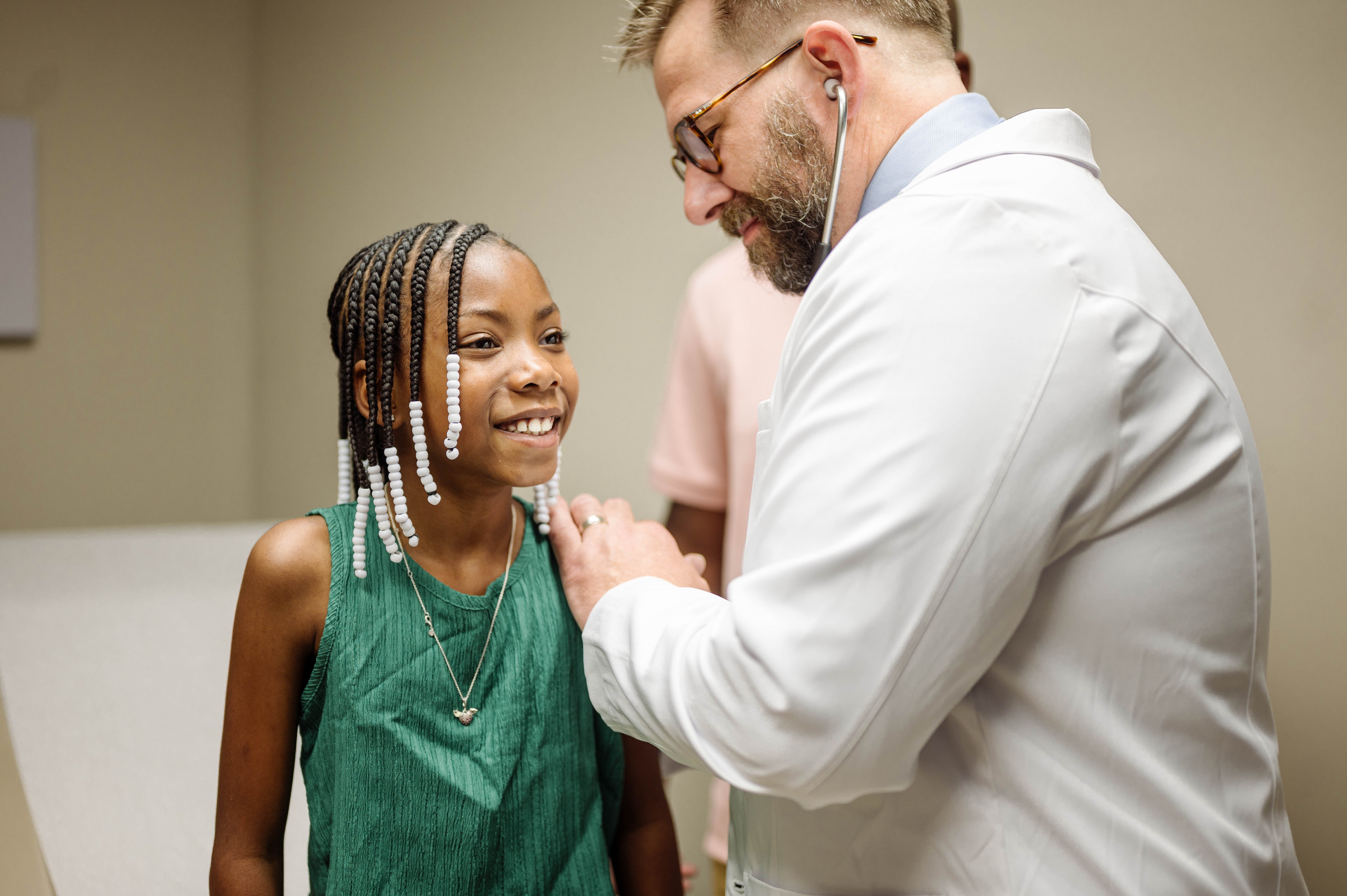 Doctor listening to little girl's breathing with stethoscope
