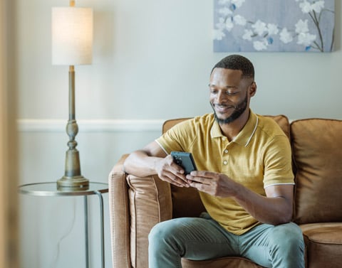 Young man on sofa using myConnection on his mobile phone