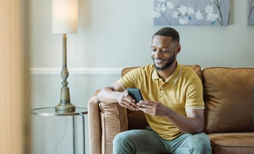 Young man on sofa using myConnection on his mobile phone