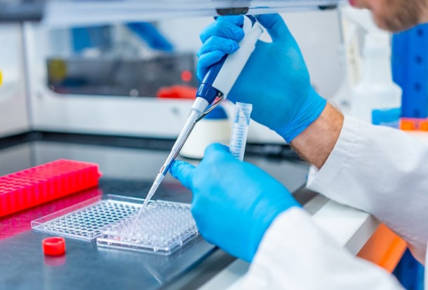 Close-up of medical lab technician using pipette to transfer samples