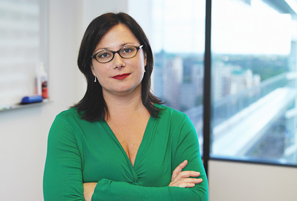 woman in a green shirt and glasses folding her arms