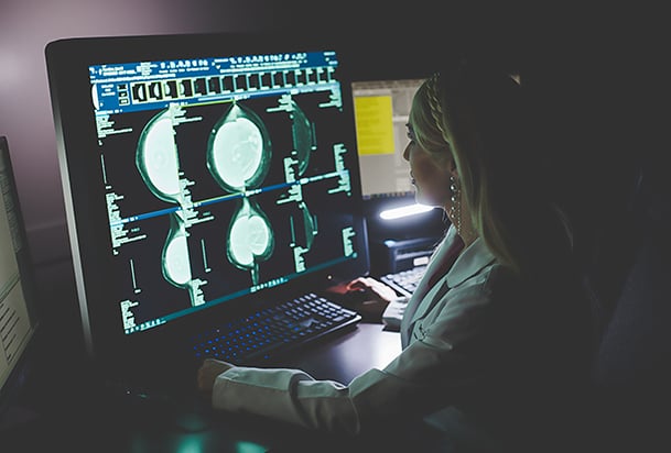 Radiologist examines mammography images on a large computer screen.