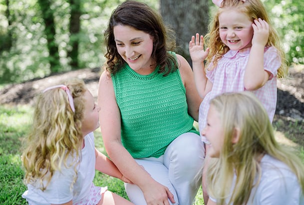 Mother wearing green surrounded by daughters
