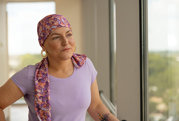 woman with a pink headscarf looking out the window