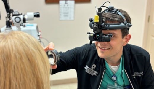 Dr. Schonbach examining a female patient's eye with a lens in the clinic