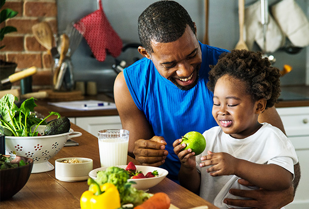 man and child cooking with fruits and vegetables