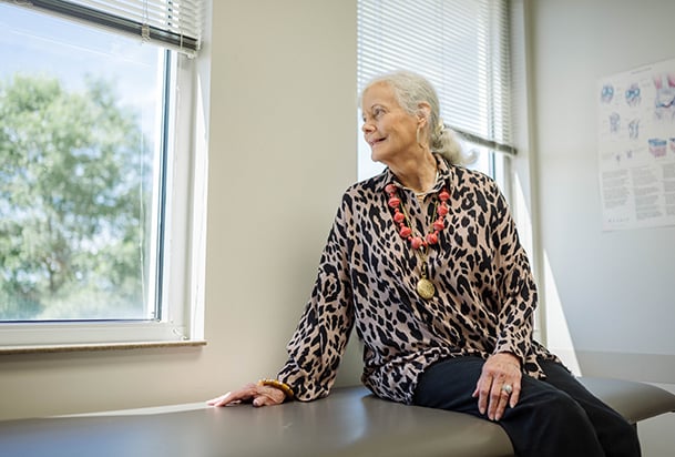 Silver-haired woman looks out window while waiting in an exam room