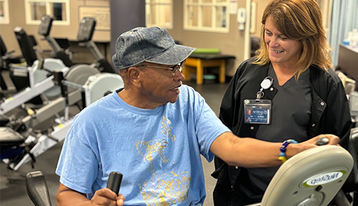 man on an exercise machine working with a healthcare worker