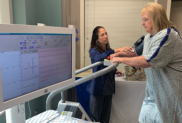 patient walking on a treadmill while healthcare worker instructs