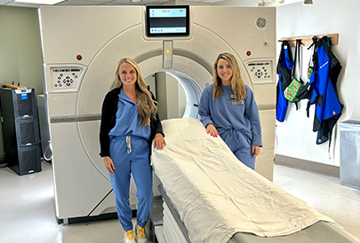 2 techs standing next to the CT Scanner