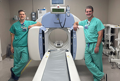 Two medical professionals next to a PET scanner 