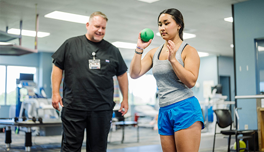 Girl doing physical therapy as therapist watches