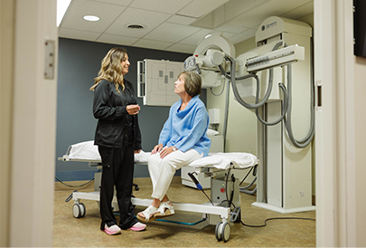 Woman sitting on a patient table talking to medical professional