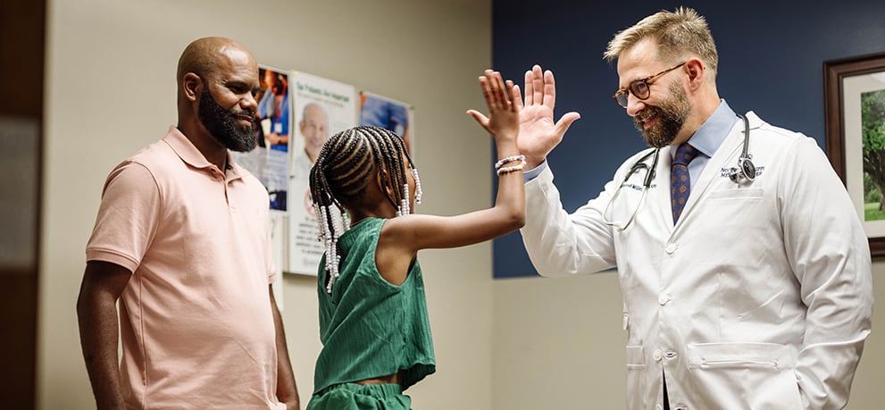 Father and daughter with doctor high-fiving