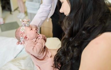 mom with long hair holding her newborn and smiling at her