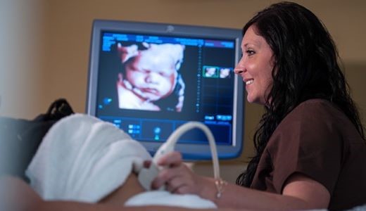 tech at maternal fetal medicine clinic performing a detailed ultrasound on a female patient