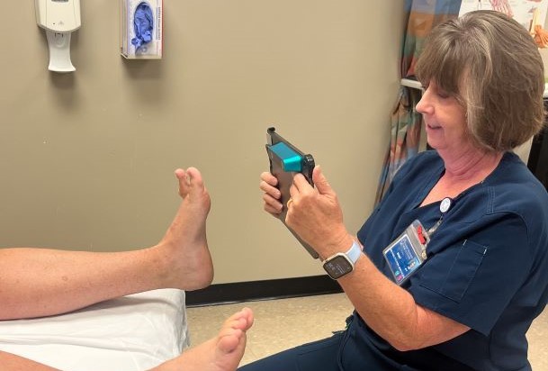 physical therapist taking measurements of a patient's foot using a hand-held device in the Foot Center