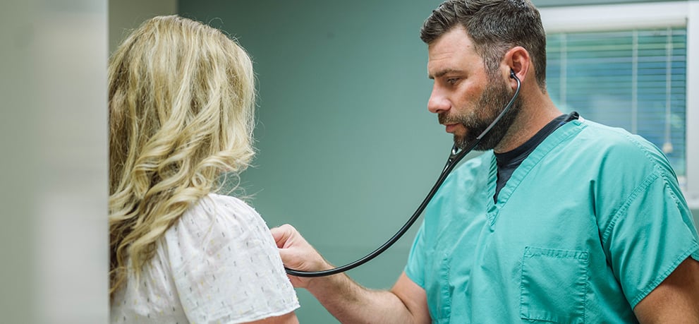 Urgent Care doctor listens to patient's chest