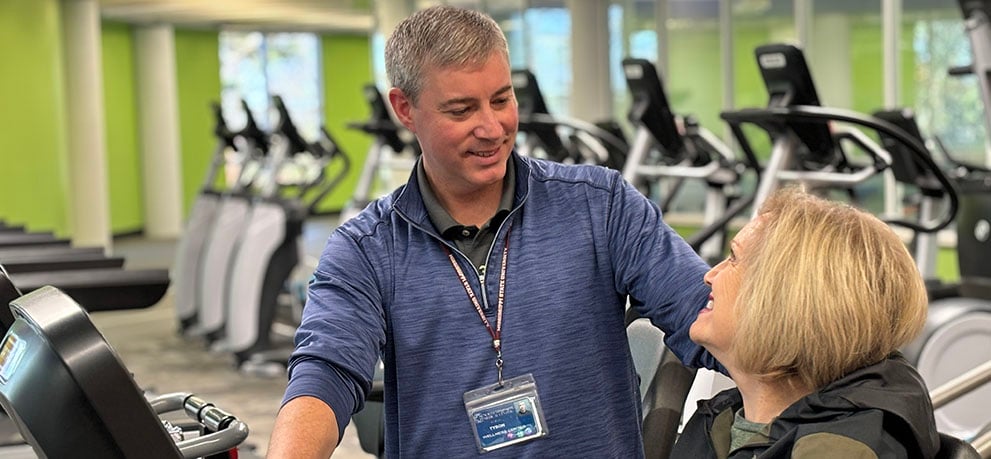 Wellness Center trainer assisting a client on exercise equipment