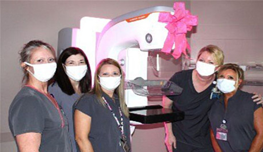 group photo in front of machine with pink ribbon