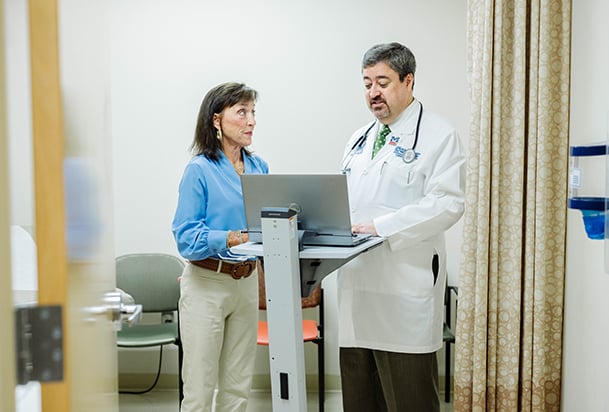 A female patient and her doctor look at a laptop together