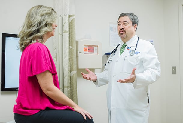 Doctor speaks to a blonde woman in a pink shirt