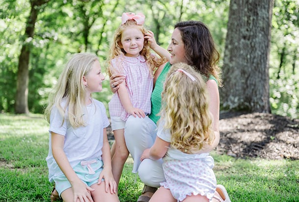Mother kneeling with her three young daughters