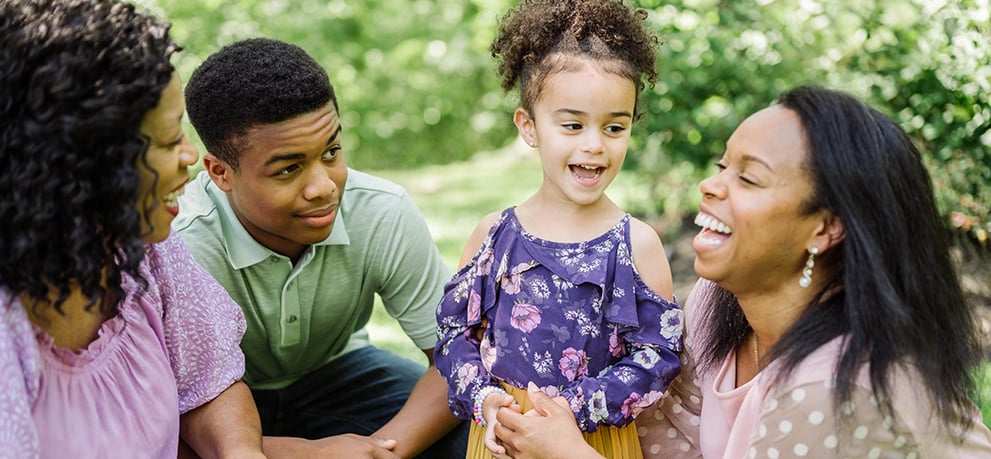 Grandmother, teen son, young daughter, and mom smiling and laughing
