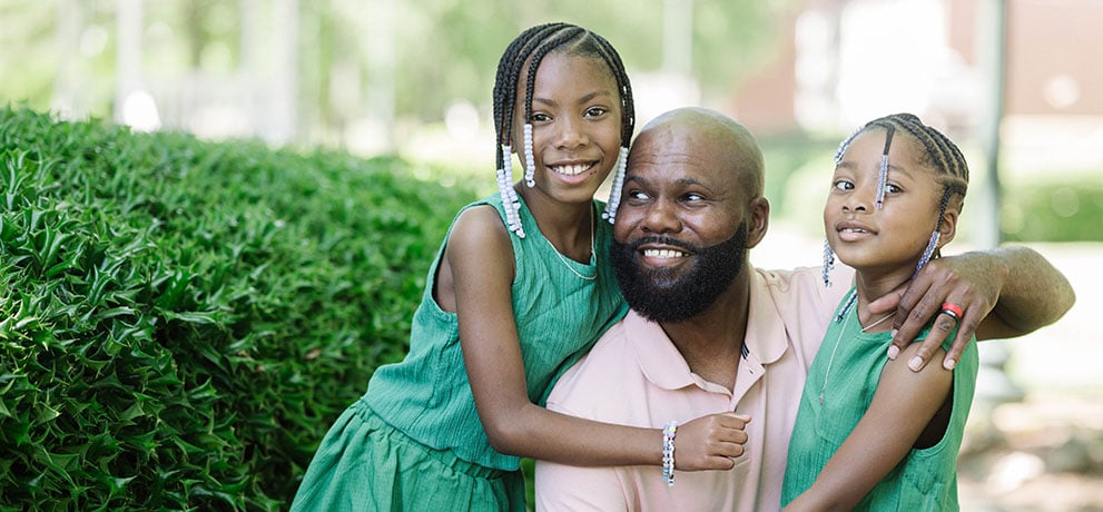 Father hugs his two daughters