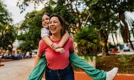 girl riding piggyback on woman's back