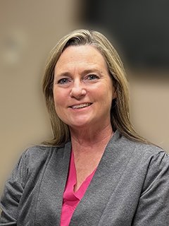 headshot of Jill Bauer, smiling with a pink shirt and gray scrub jacket on. 