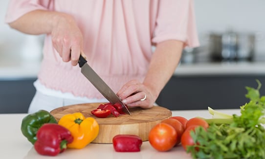 Woman in pink chopping colorful vegetables