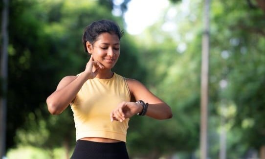 young woman checking her heart rate with two fingers on her neck
