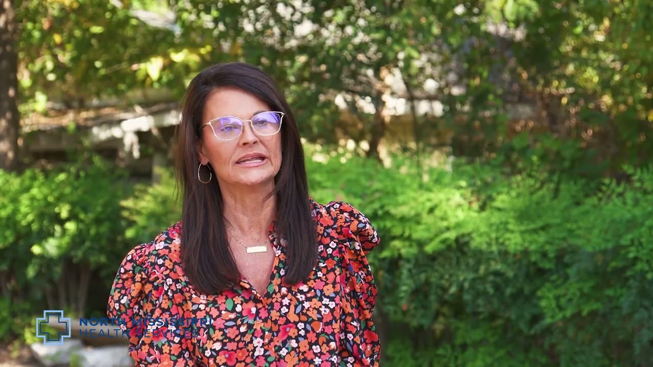 Thumbnail of Terri Green sharing her story. Beautiful green shrubs are behind her. 