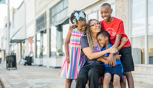 Mother and three children hugging outside of hospital