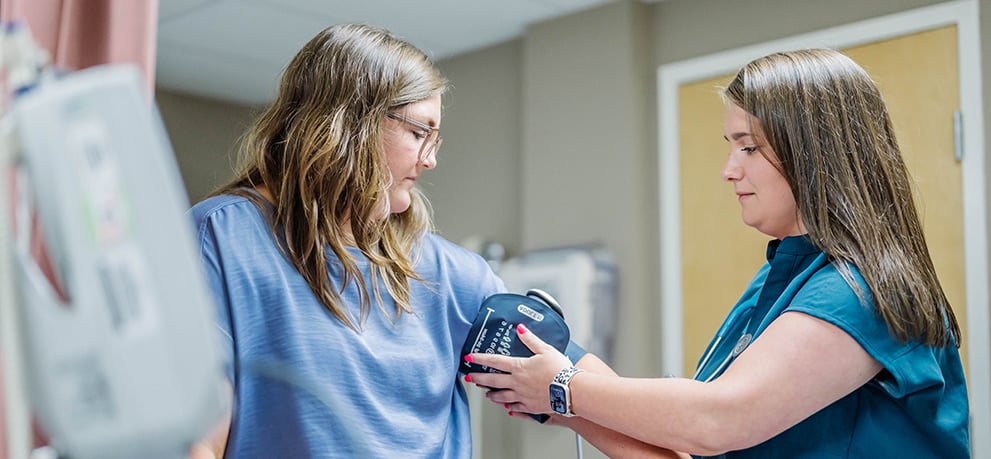 A nurse taking a patient's blood pressure in a clinic exam room